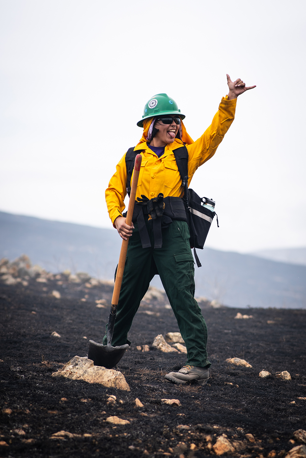 A Cal Poly student waves at a classmate while checking for hot spots following a prescribed burn on Cal Poly land.