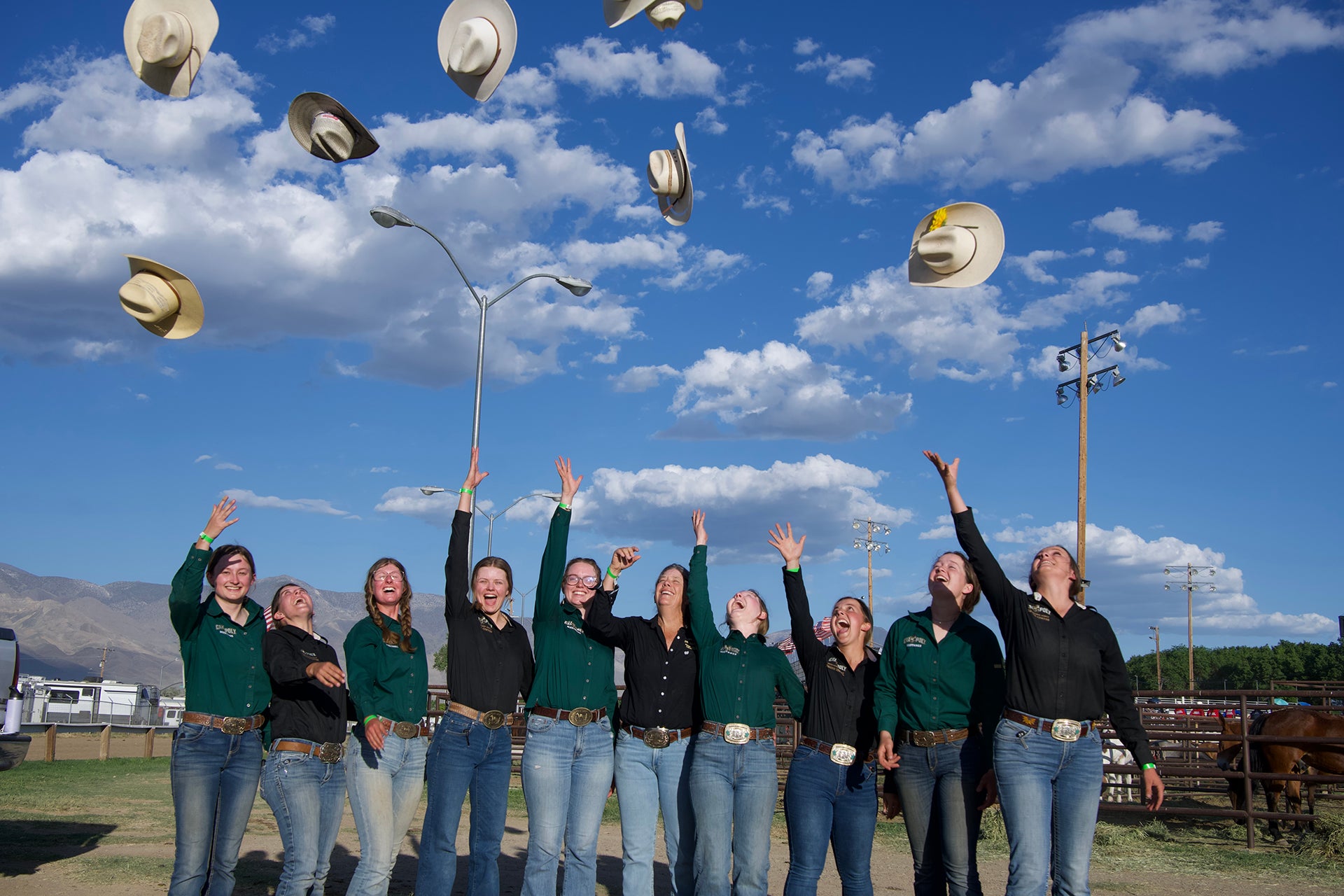 Cal Poly Mule Packing team members throw their hats in the air. 