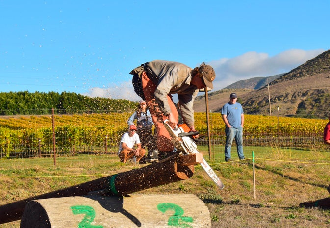 A student stands on top of a log as he participates in the Chainsawing event. 