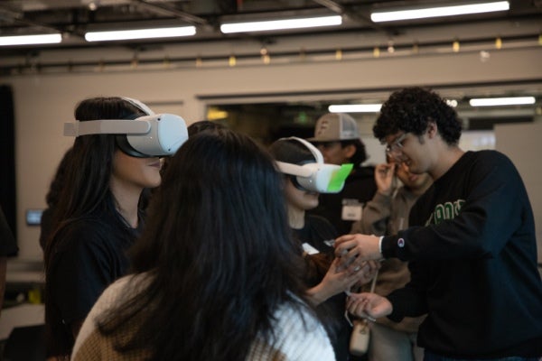 Group of students using virtual reality headsets and interacting with immersive technology during a hands-on classroom or innovation lab activity.