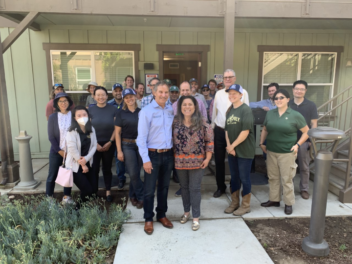 Large group of faculty, staff, and industry participants posing outside a campus building during an agricultural or educational tour event.