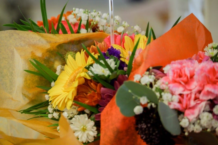 Colorful floral bouquets featuring bright gerbera daisies, carnations, and mixed flowers wrapped in decorative paper arrangements.