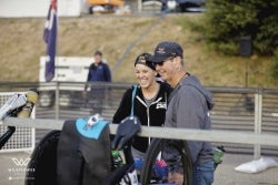 Two people smile and talk beside bicycles during a race or cycling competition event.