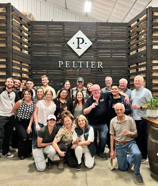 Large group photo inside Peltier Winery during a winery and vineyard industry tour.