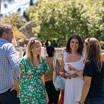Guests socializing and talking together at an outdoor graduation reception on a sunny day.