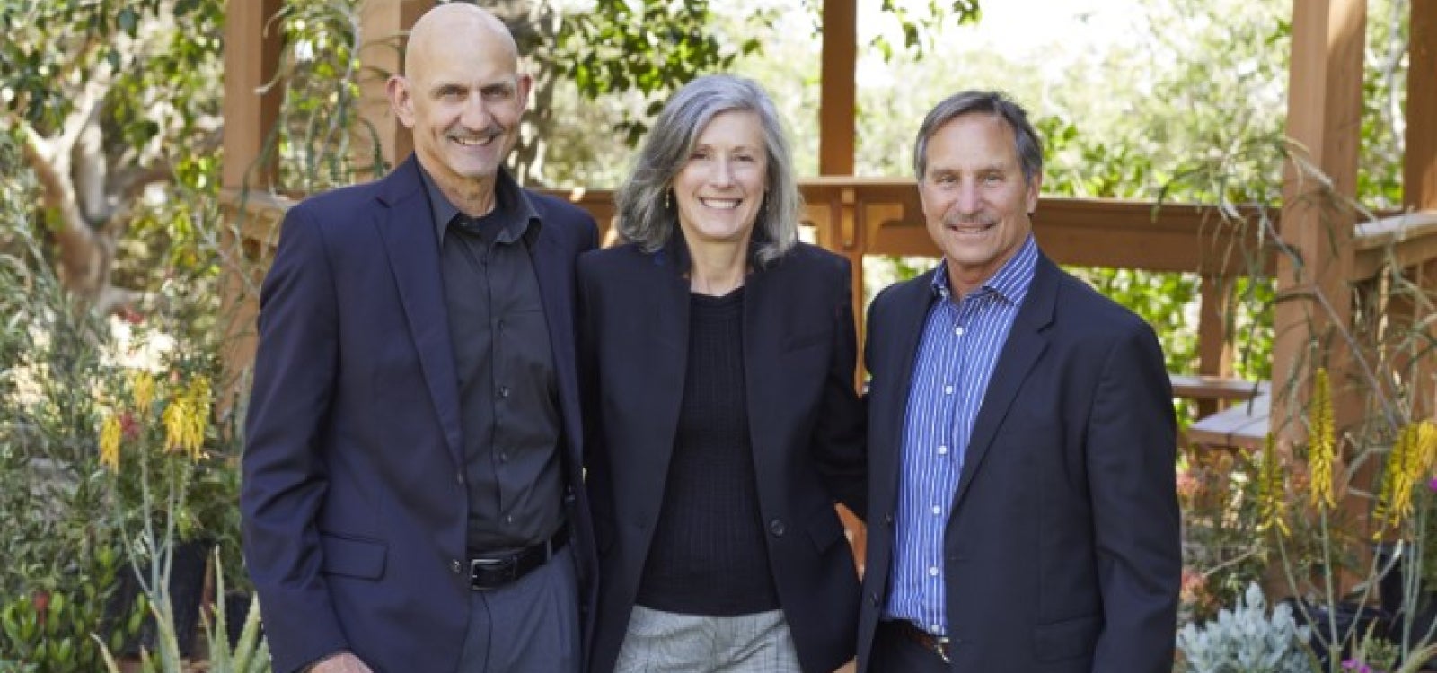 Three people, shoulder to shoulder, pose for a photo.