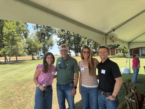 The dean of the College of Agriculture, Food and Environmental Sciences stands with alumni during an event at Grimmway Farms. 