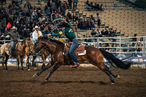 A female rodeo contestant from Cal Poly competes in breakaway roping.