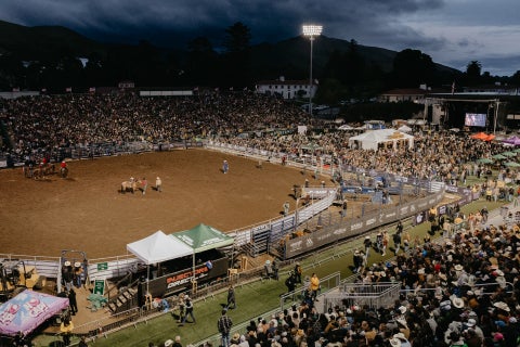 A photo showing a sold out Spanos Stadium at Cal Poly with the Poly Royal rodeo arena in the middle of the field. 