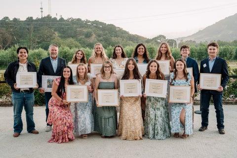 A group of 14 students stand with the dean for a photo during the Student Leadership Awards banquet. 