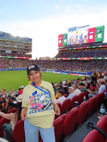 A student wearing a yellow tee-shirt that reads "OLE, OLE, OLE, OLE, OLE, OLE, OLE, OLE" stands next to seats in a stadium during a World Cup match.