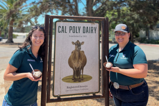 Marissa Johnston and Jenna Bates stand by the Cal Poly Dairy sign. 