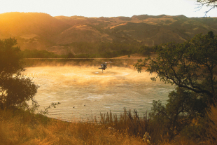 A helicopter takes water out of a lake to support wildfire supression.