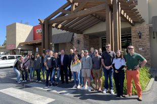 Students and faculty stand in front of a local grocery store. 