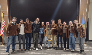 A group photo of the Cal Poly Soil Judging Team with their championship banner. 