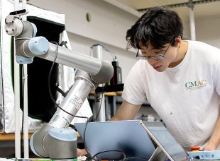 A student works on a automated arm that will be used to harvest grapes.  