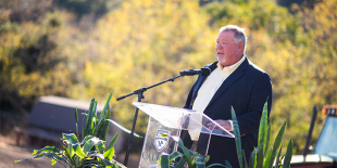 A man speaking into a microphone during a CAFES ceremony. 