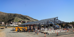 Construction of solar panels with tractors and trucks in the background