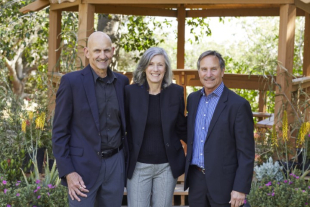 Three people, shoulder to shoulder, pose for a photo.