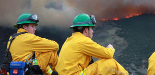 Two of Cal Poly fire students sitting as they watch the controlled fire