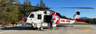 A Helitack crew member posing with a Cal Fire helicopter  