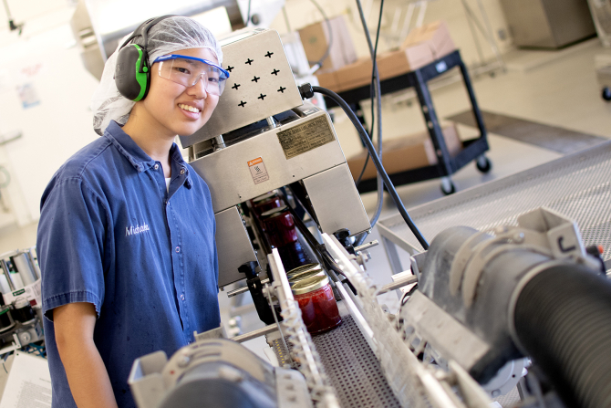 A student smiles as she works the line making Cal Poly Jam. 
