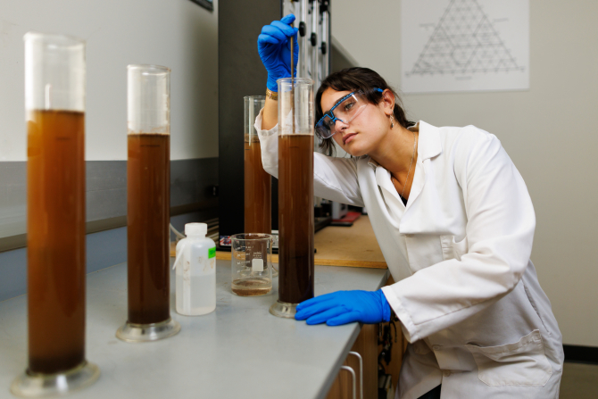 An environmental earth and soil sciences student in the lab after collecting soil samples on campus.