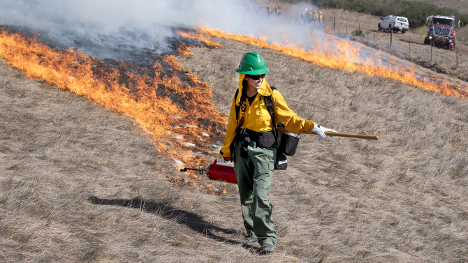 A Cal Poly student smiles while working a prescribed burn. 
