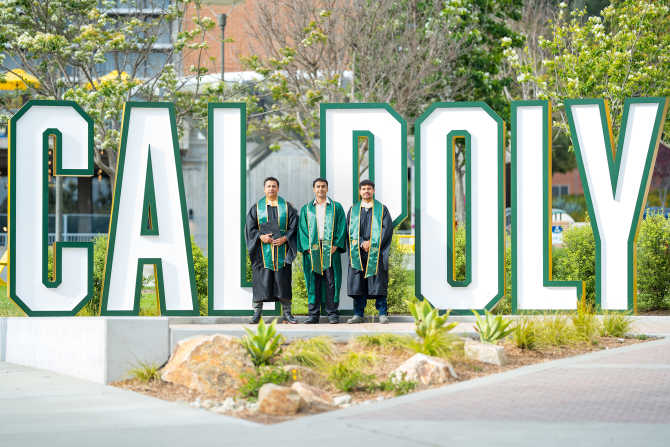 The Godoy graduates stand in front of the Cal Poly sign. 