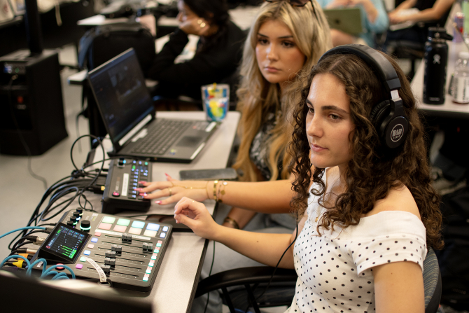 Students run the audio program during a podcast class.