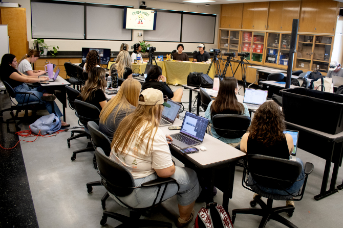 A classroom full of students produce a podcast. 