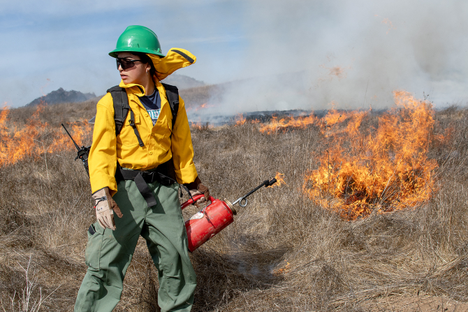 A student participates in a prescribed burn on Cal Poly's campus. 