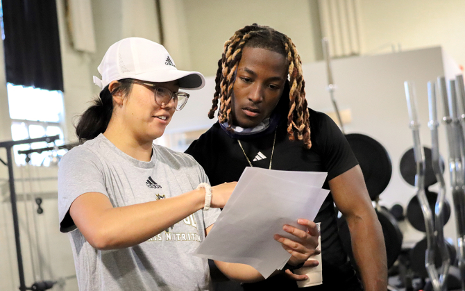 A student athlete goes over test results with a nutrition student. 
