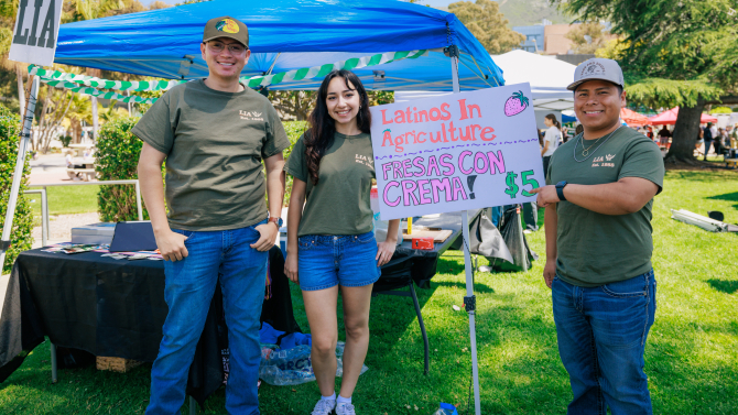Students at the Latinos in Agriculture booth smile at the camera. 