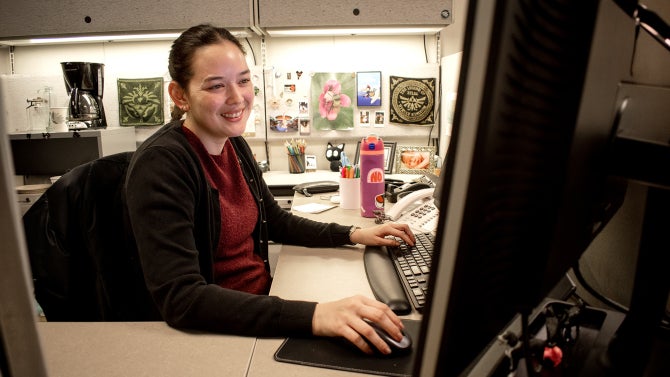 An academic advisor works at her desk top computer. 