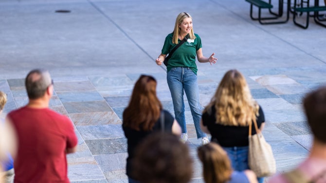 A student Poly Rep talks in front of a group of visitors during a tour of campus. 