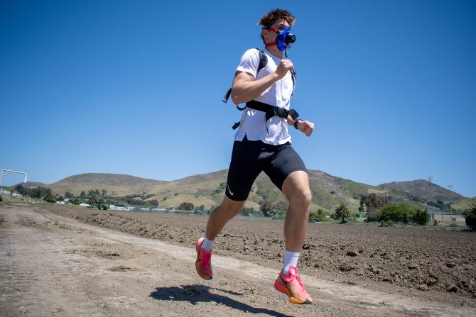 A student runs through a field with a respirator during a study. 