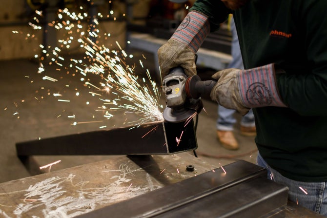 A student uses a grinder to build customized equipment for a project. 