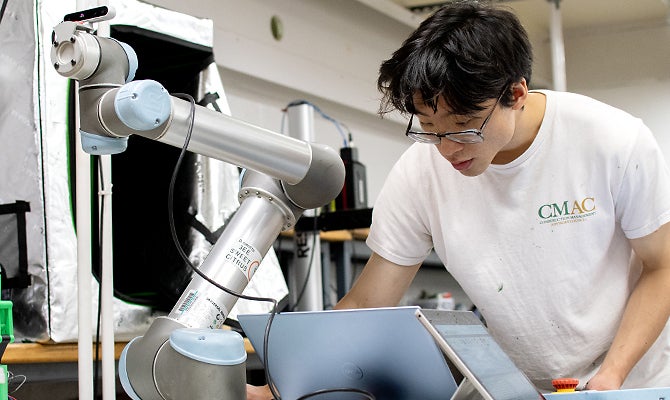 A student works on a automated arm that will be used to harvest grapes.  