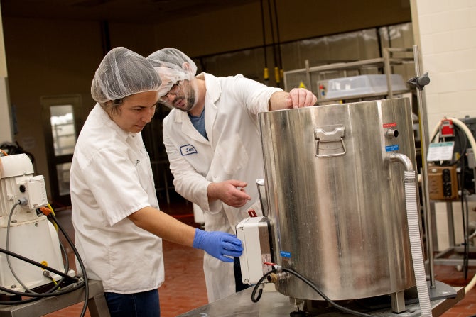 A graduate student works beside professional staff on a research project in the Dairy Products Technology Center. 