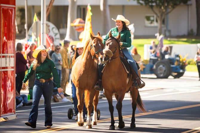 Animal Science students smile as they ride horses in the Cal Poly Open House parade.  